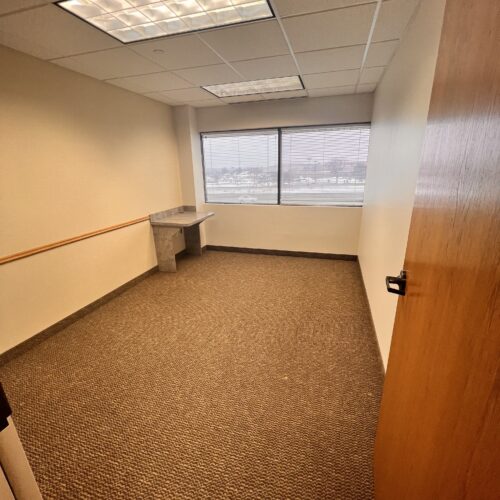 An office building with large windows and ample parking available for lease.