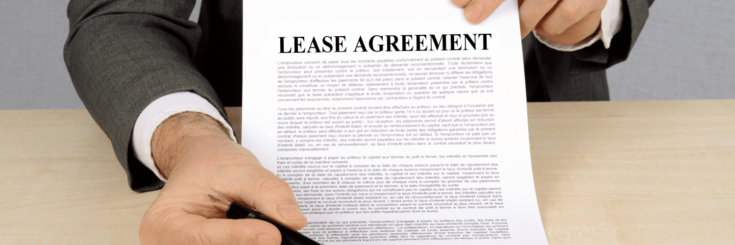 Photo of a person's hand signing a commercial real estate lease contract with a pen